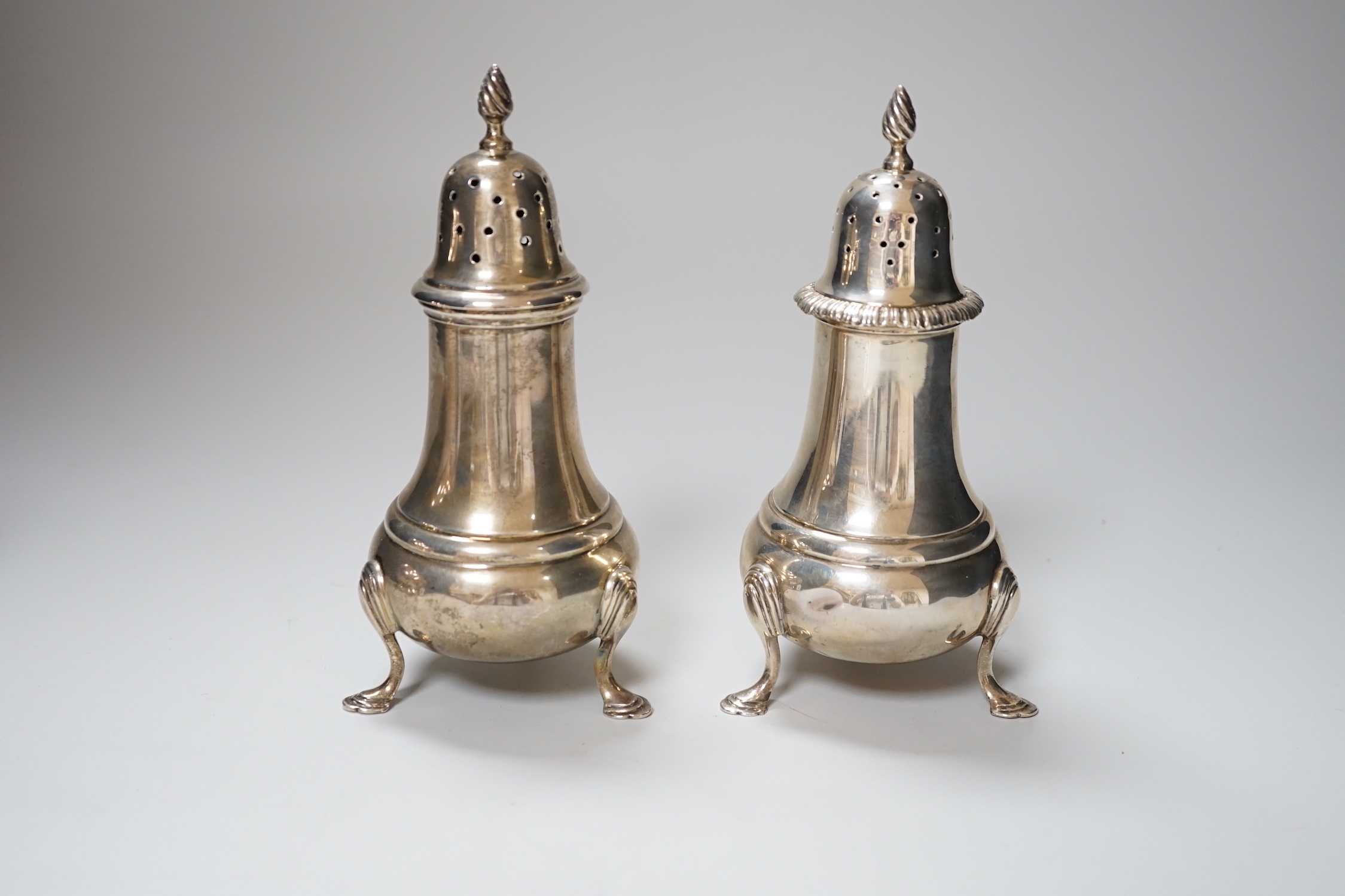 A near pair of George VI silver casters, with baluster bodies and pad feet, makers Elkington & Co, Birmingham 1936 and 1939, 16cm, 366 grams